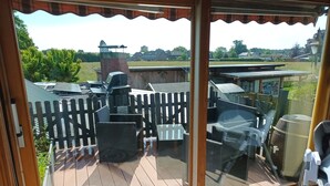 Un patio techado con mobiliario exterior, una parrilla de barbacoa y una terraza de madera.