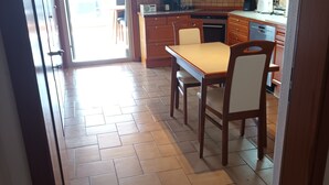 Una cocina con armarios de madera, un salpicadero de azulejos y una zona de comedor con una mesa y sillas.