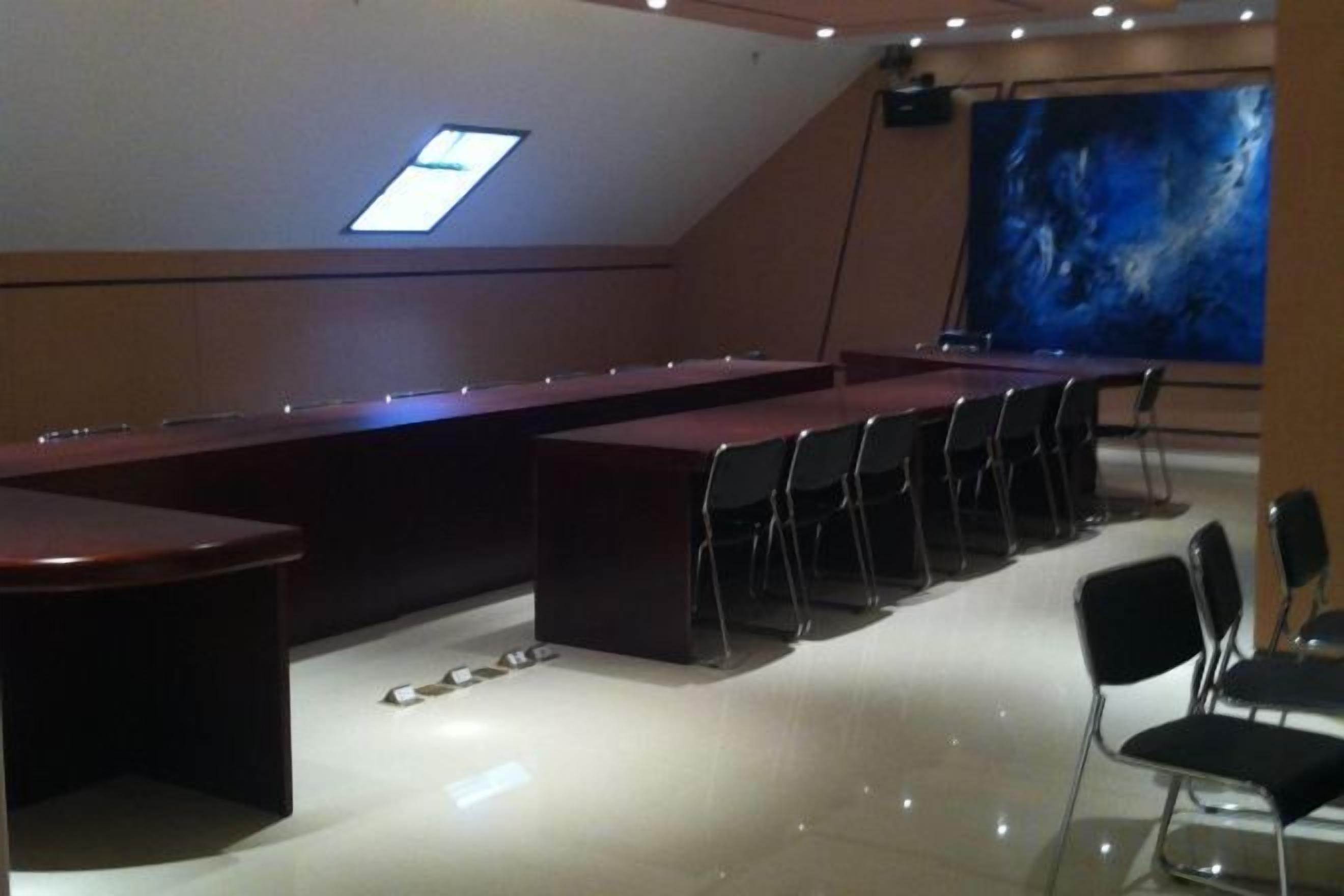A conference room with a long table, chairs, and a projector screen.