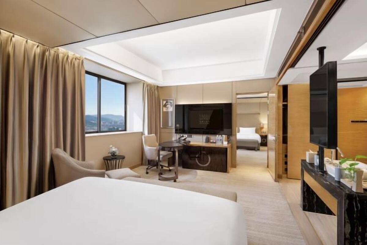 Ein Hotelzimmer mit Bett, Schreibtisch, Stuhl, Fernseher und Blick ins Freie.