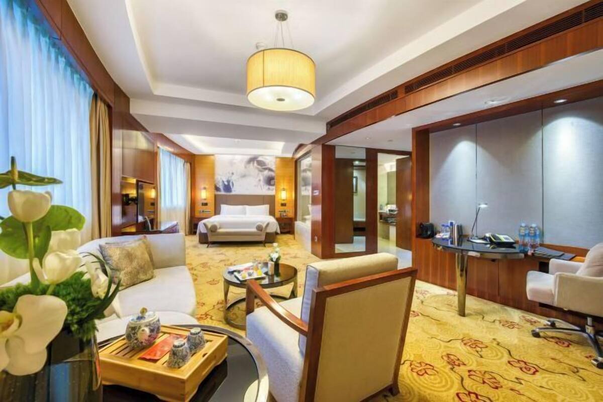 Ein Hotelzimmer mit einer Couch, einem Sessel, einem Esstisch und einem Bett.