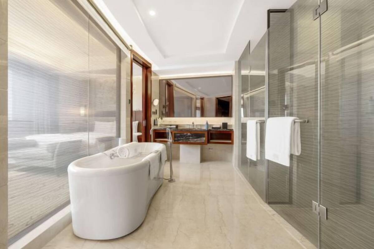 Ein modernes Badezimmer mit einer großen Badewanne, einer Duschkabine aus Glas und einem Waschtisch mit Spiegel.