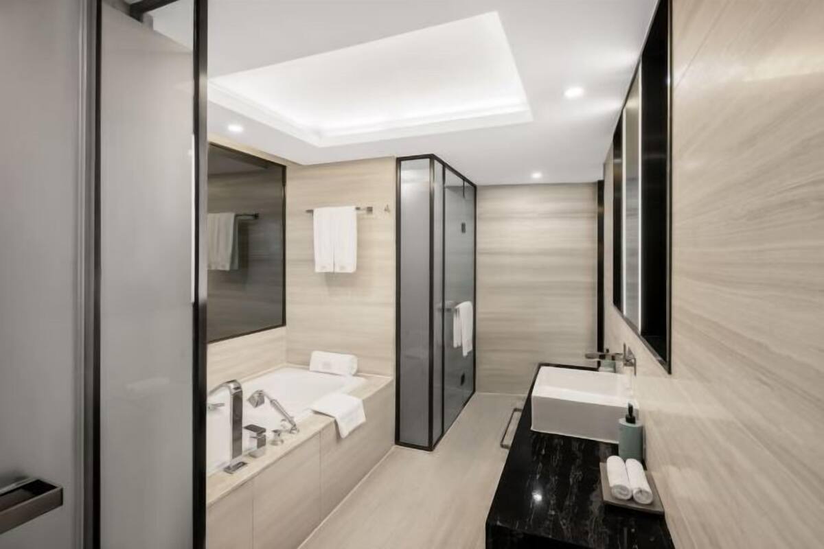 Ein modernes Badezimmer mit Badewanne, separater Duschkabine, Waschtisch mit Spiegel und Toilette.