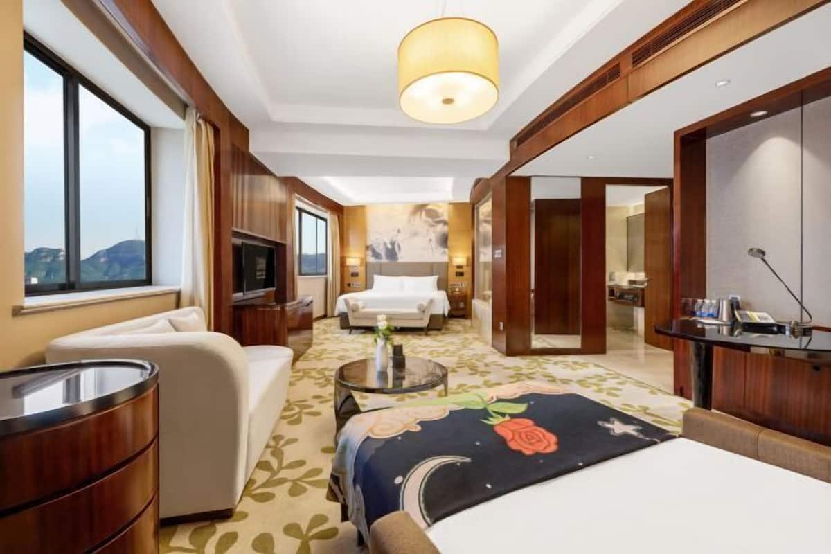 Ein Hotelzimmer mit Bett, Sofa, Fernseher und einem großen Fenster.
