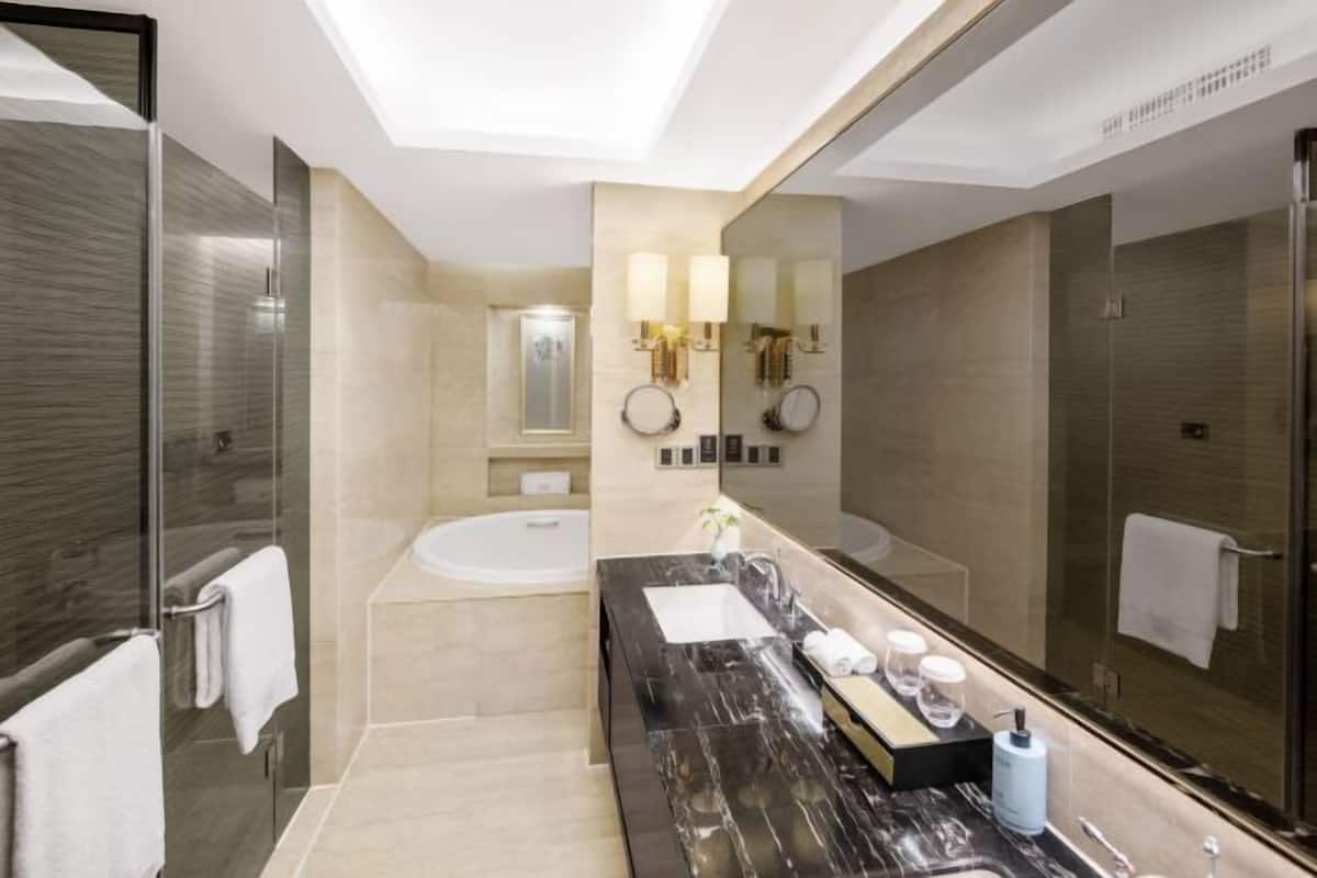 Ein modernes Badezimmer mit einer Badewanne, einem großen Spiegel und einem Waschtisch mit Marmorplatte.