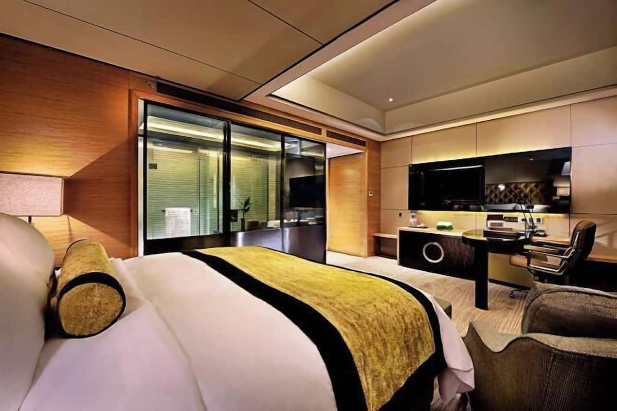 Ein modernes Hotelzimmer mit einem großen Bett, einem Schreibtisch, einem Fernseher und Blick auf die Stadt.