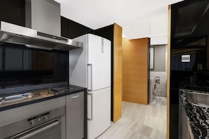 A modern kitchen with a stainless steel range hood, a built-in oven, and a white refrigerator.