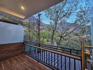 A balcony with a wooden floor and metal railing, overlooking a mountainous landscape with trees and a clear sky. - Aghor Guest House (Dharamshala)