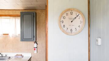 A kitchen with a wooden cabinet, a sink, and a wall-mounted clock.