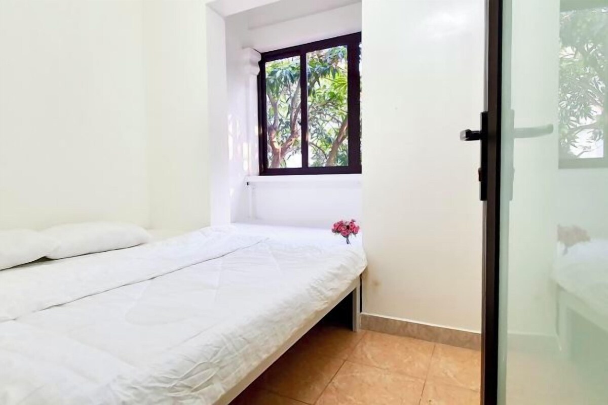 A small, single-bed room with a window and a door.
