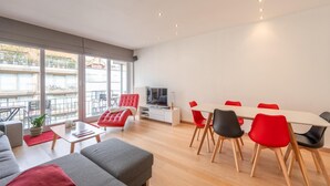 A modern living room with a sofa, ottoman, dining table with chairs, and a TV. - Sunny Stay by the Seaside (Knokke-Heist)