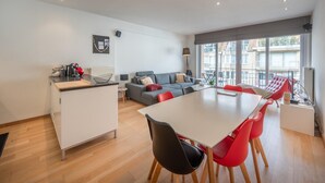 A modern living space with a dining area, a sofa, and a balcony with a view. - Sunny Stay by the Seaside (Knokke-Heist)