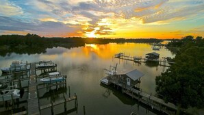 A marina with docked boats and a small building, surrounded by trees and a calm lake during sunset. - Boat Slip - Pool- Screened balcony- Water front. 30 DAY MINIMUM STAY. (Gulf Shores)