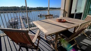 A wooden table and chairs on a balcony with a view of a marina and boats. - Boat Slip - Pool- Screened balcony- Water front. 30 DAY MINIMUM STAY. (Gulf Shores)