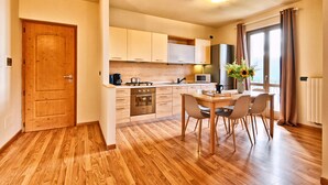 Une cuisine moderne avec des meubles en bois, une table à manger avec des chaises et une grande fenêtre avec des rideaux.