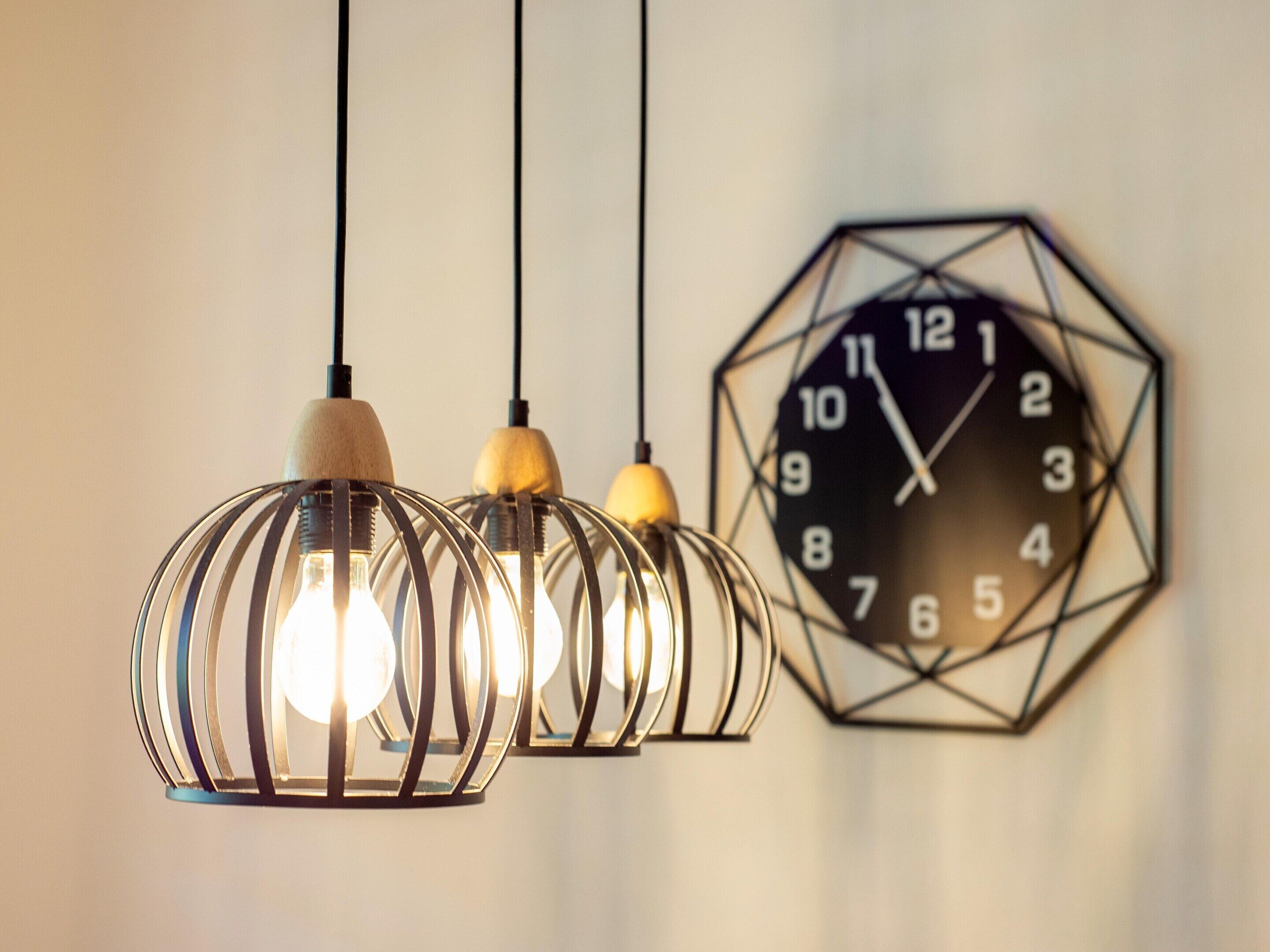 Three hanging light fixtures with exposed bulbs and a geometric wall clock.