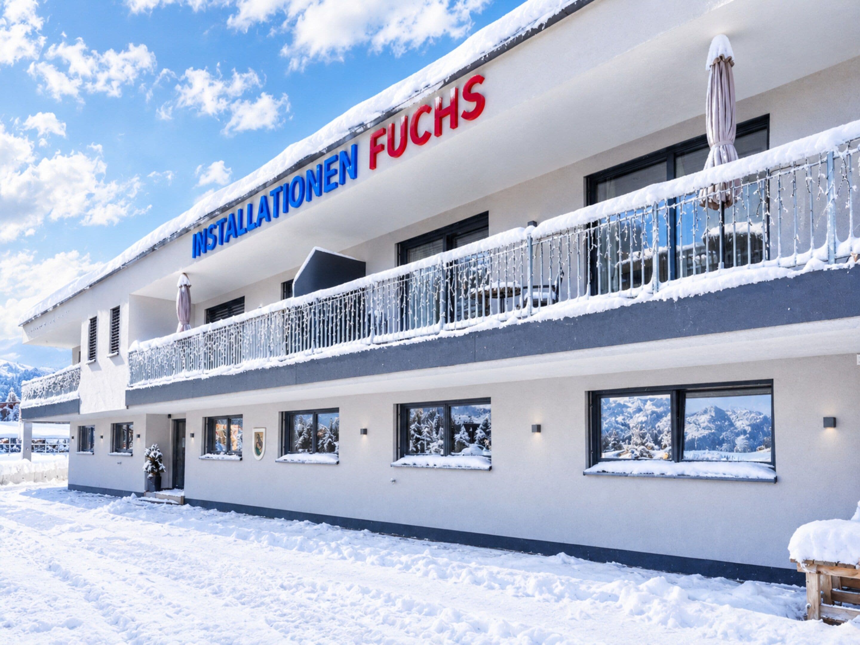 Un hotel con un cartello che recita 'INSTALLATIONEN FUCHS' e un balcone con ringhiere coperte di neve.