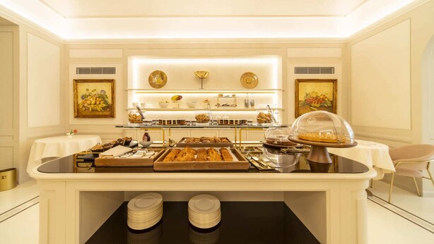 A buffet setup with various food items, a chandelier, and artwork on the walls.