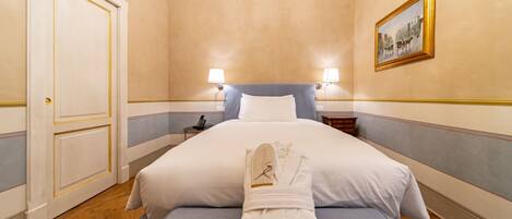 A hotel room with a large bed, bedside lamps, a framed picture on the wall, and a neatly folded robe on the bed.