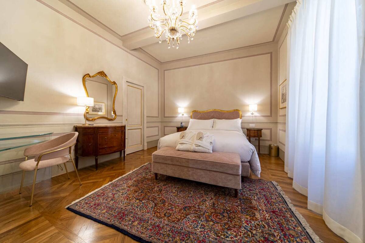 Un dormitorio con cama, cómoda, silla, candelabro y una alfombra grande.