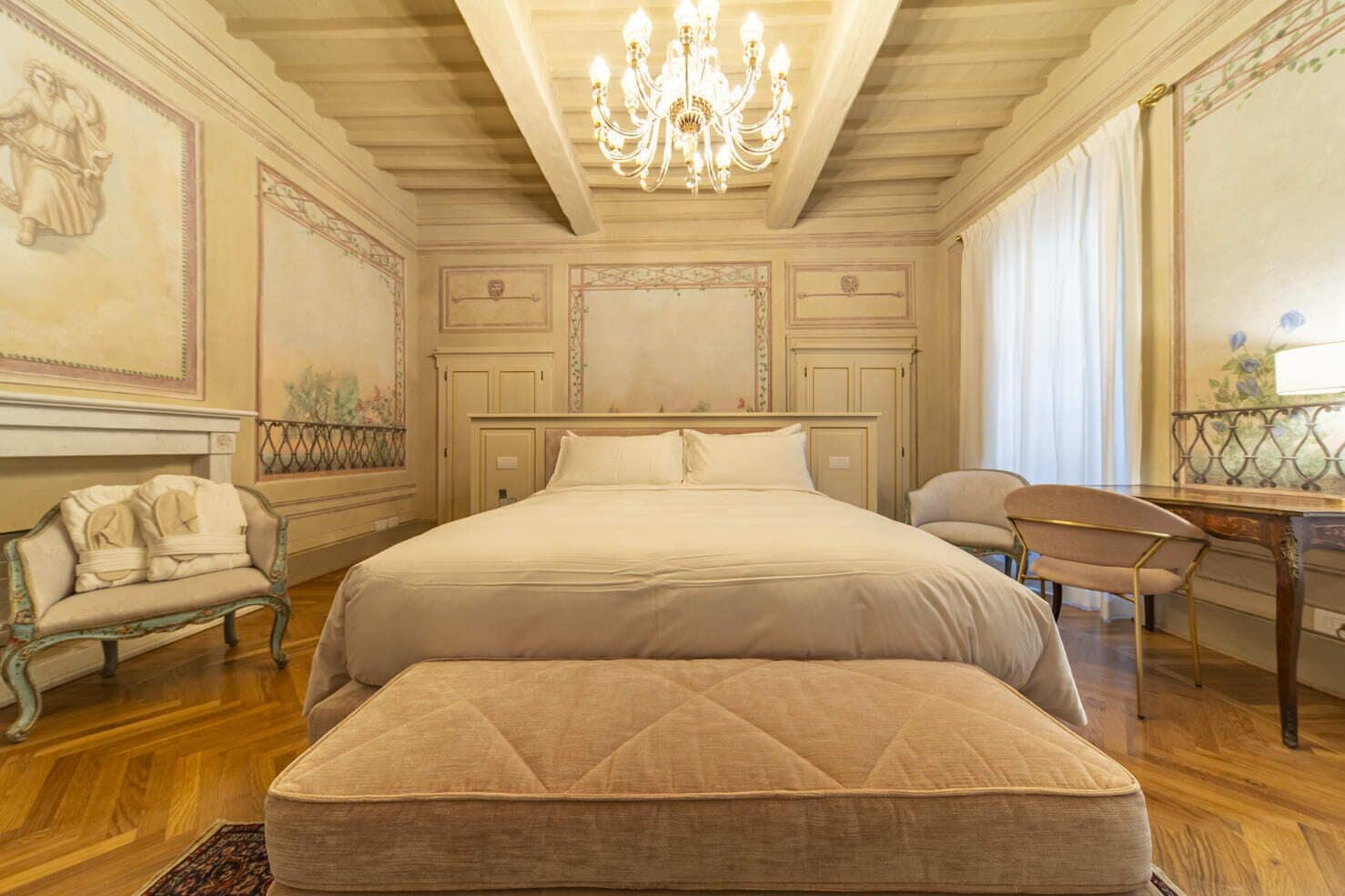 Une chambre spacieuse avec un grand lit, un coin salon avec un fauteuil et un bureau.