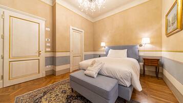 Ein Schlafzimmer mit Bett, Nachttisch, Stuhl und einer Chandelier.