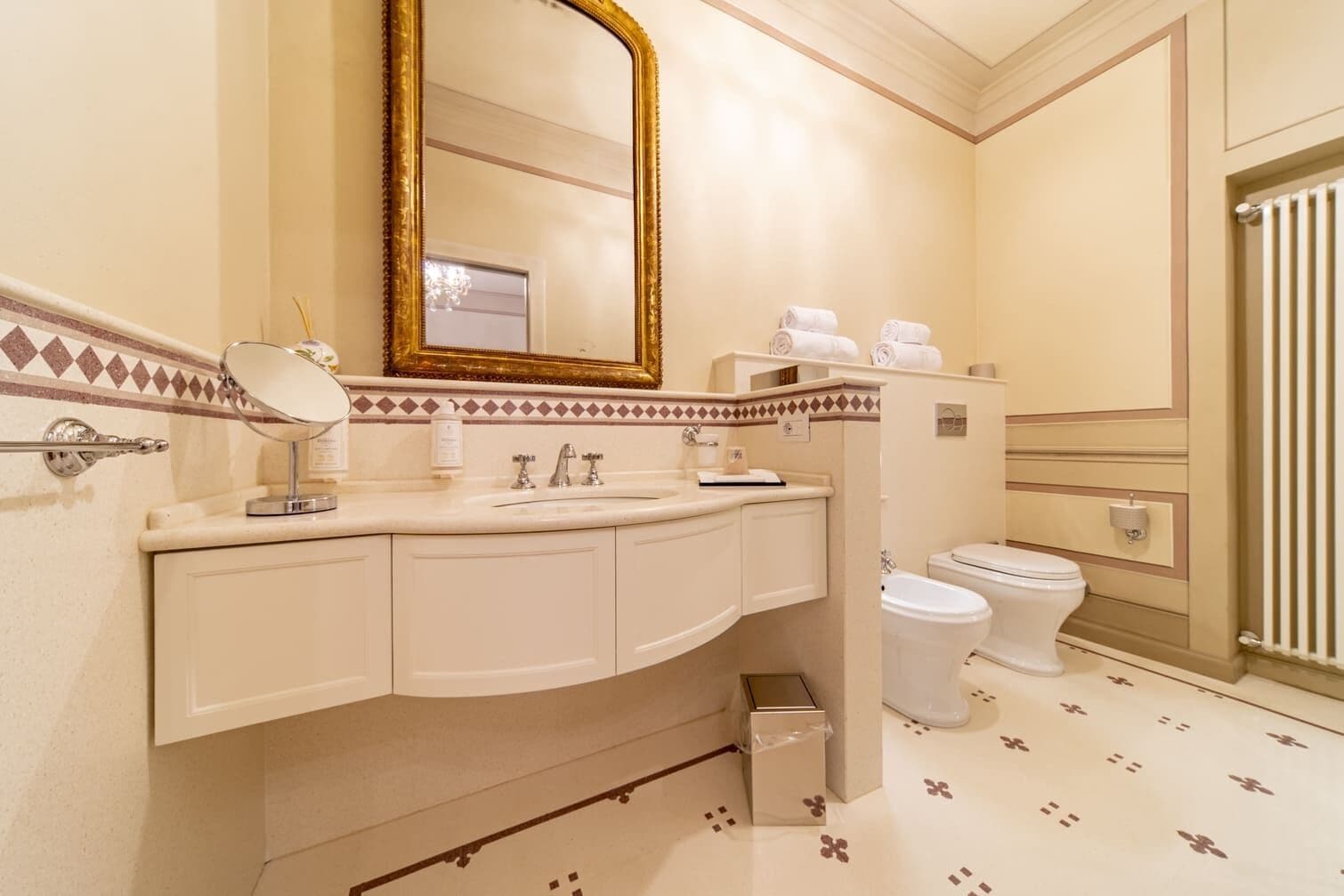 Un baño con lavamanos blanco, espejo, inodoro y bidé.