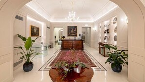 A spacious hallway with a round wooden coffee table, a chandelier, and potted plants.