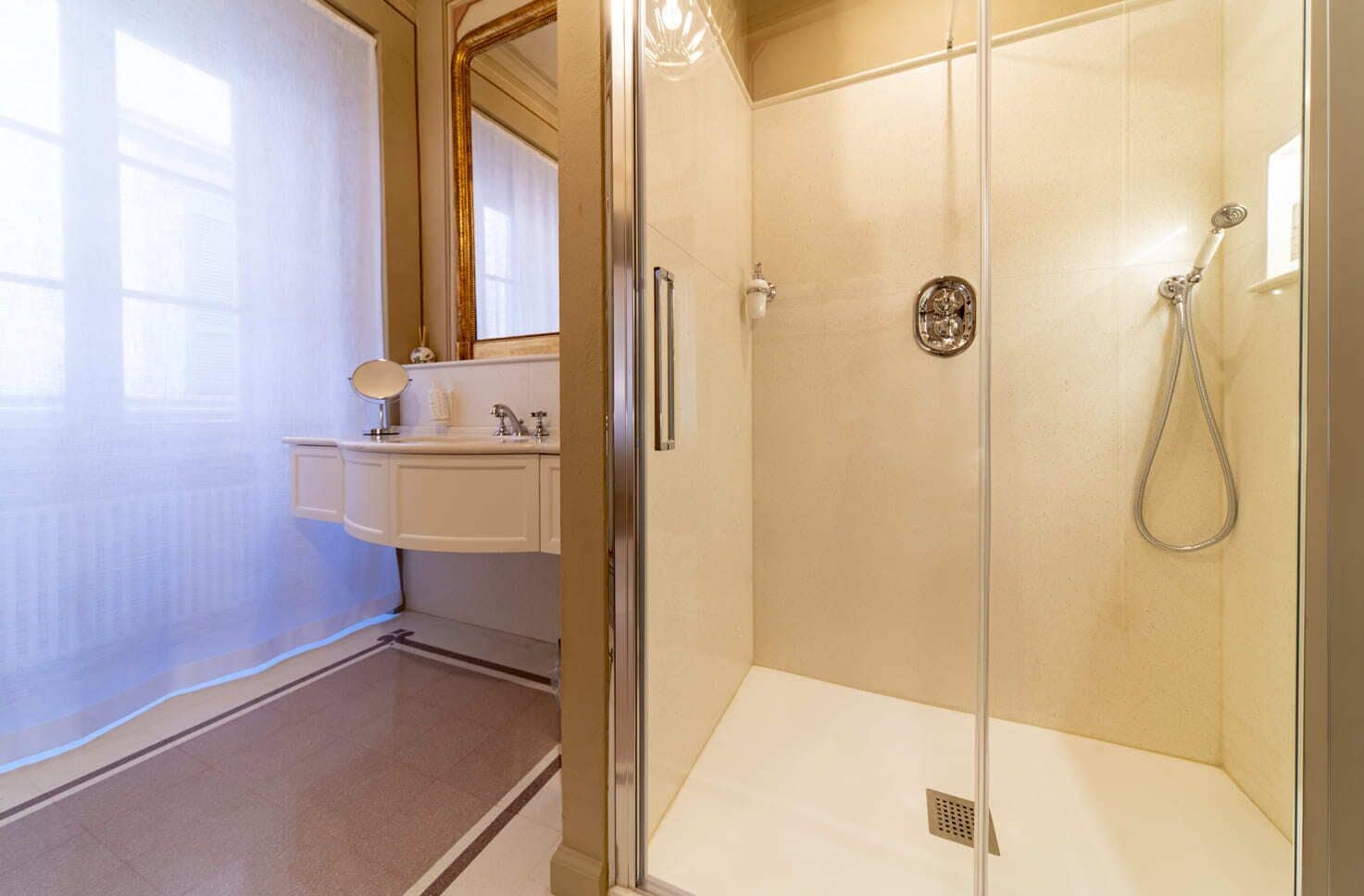 A bathroom with a glass shower enclosure, a sink with a mirror, and a toilet.