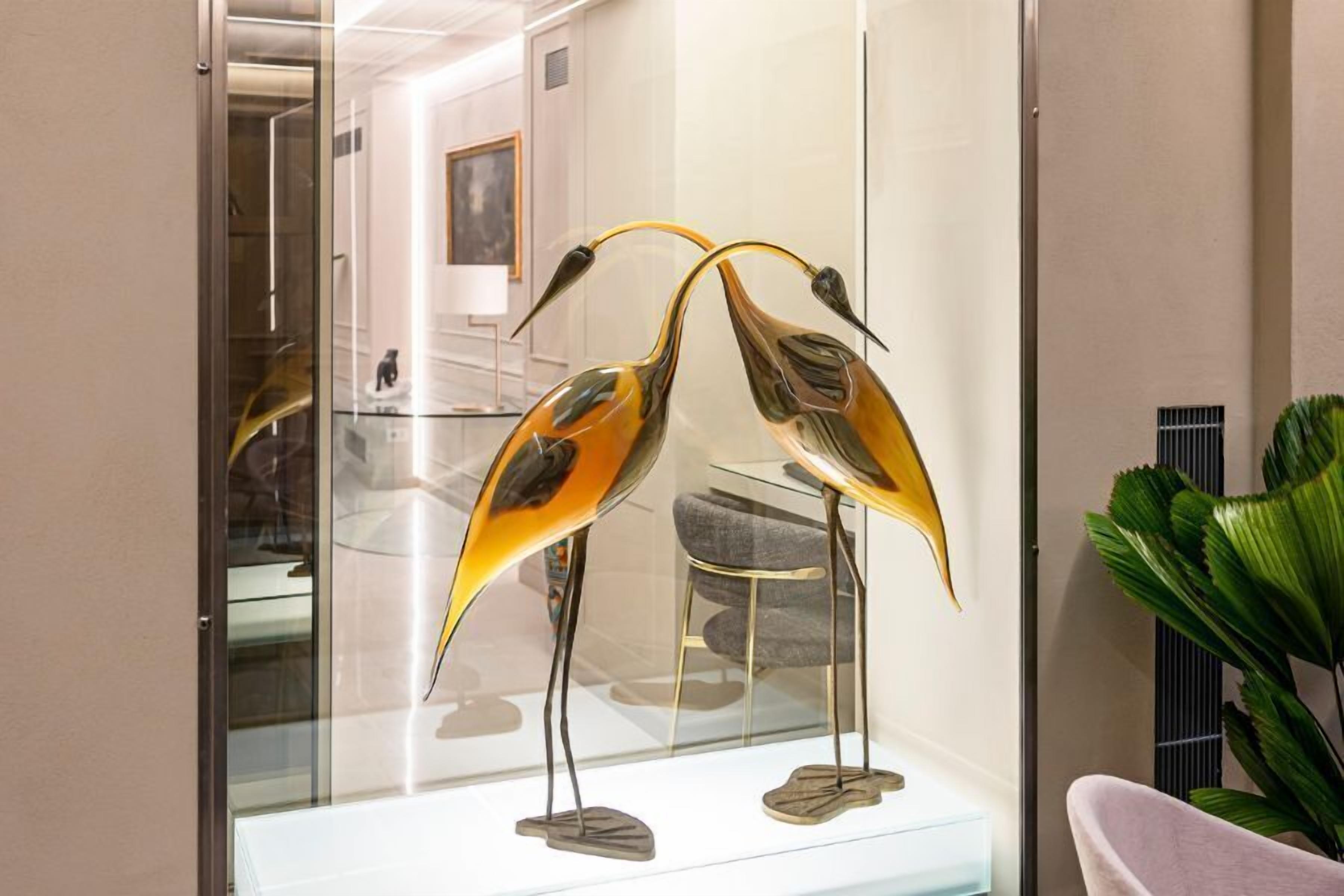 Un intérieur moderne avec une vitrine en verre contenant deux sculptures de verre représentant des oiseaux.