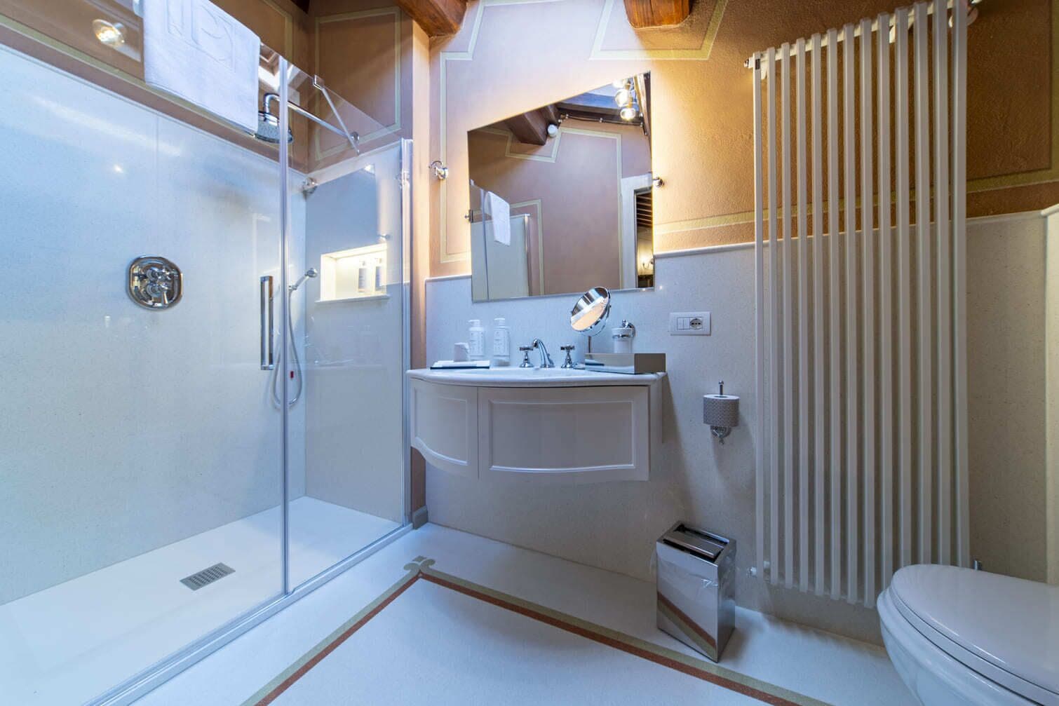 A compact bathroom with a glass shower enclosure, a white sink with a mirror, and a toilet.
