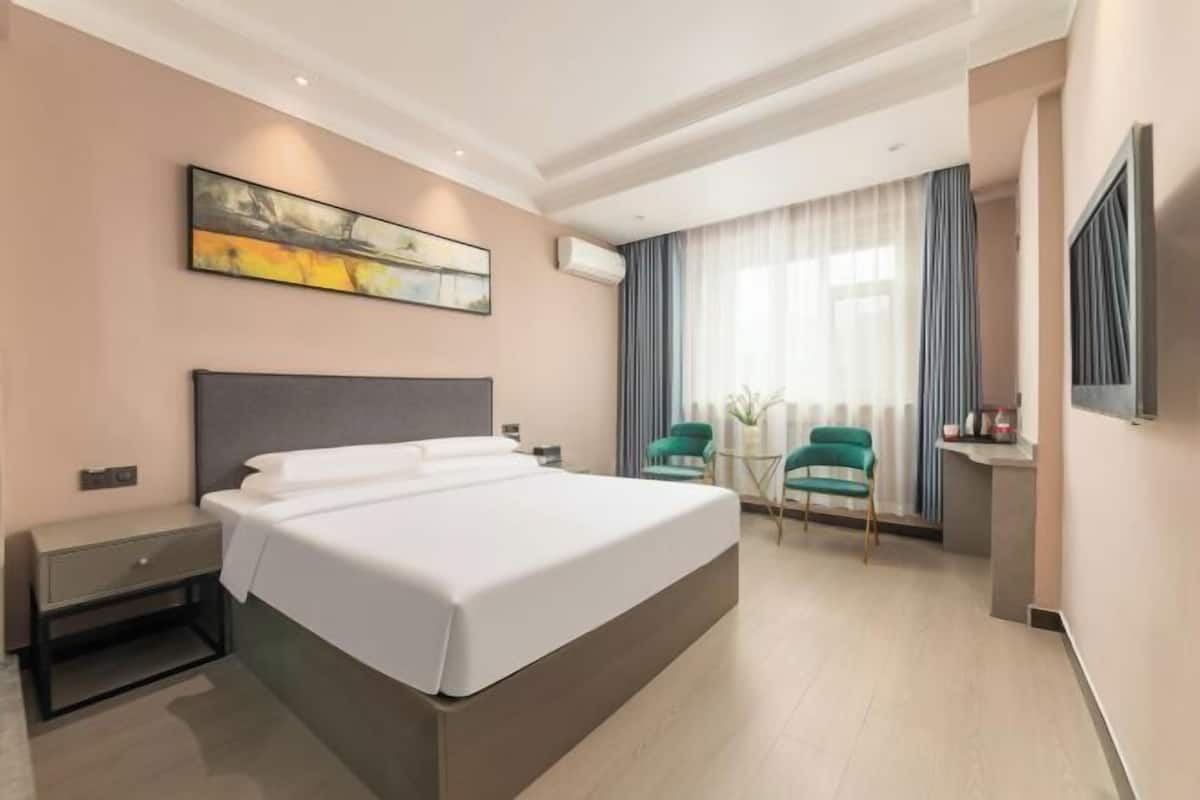 Een moderne hotelkamer met een groot bed, een bureau, een stoel en een raam met gordijnen.