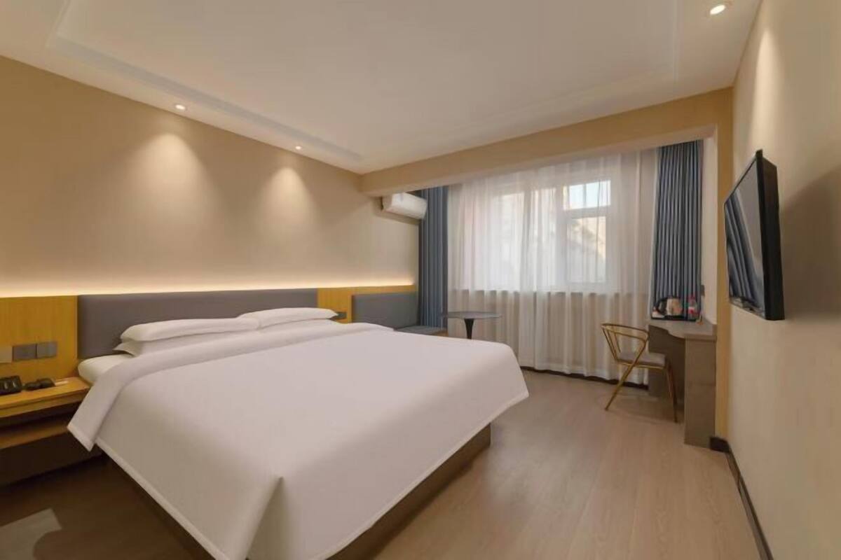 Een hotelkamer met een groot bed, een bureau met stoel en een televisie aan de muur.