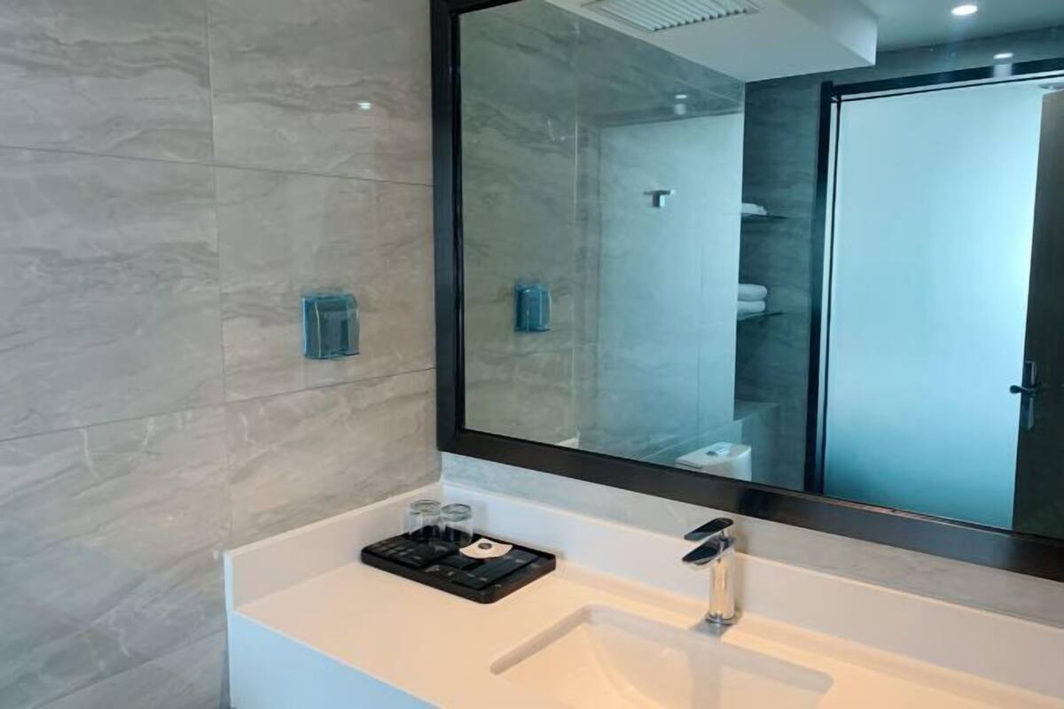 Een moderne badkamer met een grote spiegel, een witte wastafel en een douchecabine van glas.