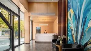 A modern reception area with a marble reception desk, a large abstract painting, and a receptionist. - Home Inn Cloud Four Seasons Hotel (Taiyuan Liuxiang Bell Tower Street Scenic Area Branch) (Taiyuan)