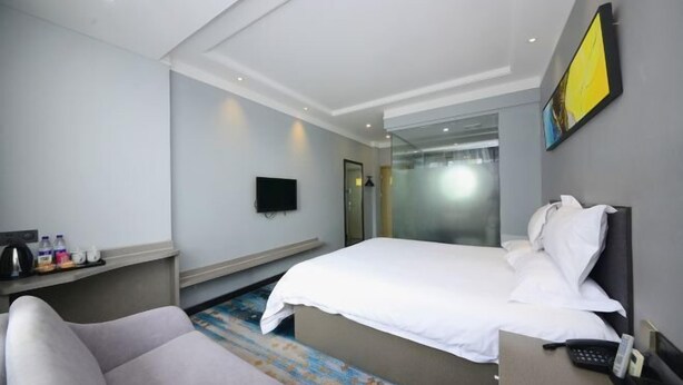 A hotel room with a bed, a desk with a phone, a chair, a TV, and a bathroom visible through a glass door. - Home Inn Cloud Four Seasons Hotel (Taiyuan Liuxiang Bell Tower Street Scenic Area Branch) (Taiyuan)