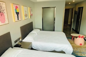 Ein Hotelzimmer mit zwei Betten, einem kleinen Tisch und einer Tür zu einem Flur.