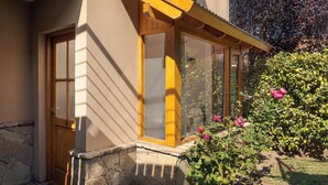 A house with a stone foundation, a wooden door, and a window with a yellow frame. - Departamento en el centro para 4 pax (San Martín de los Andes)