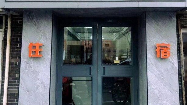 A hotel entrance with a glass door and two orange signs on either side. - Tuyou Shuxiang Homestay (Lanzhou)