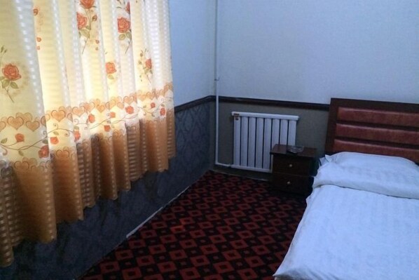A room with a bed, a radiator, and a window with curtains. - Tuyou Shuxiang Homestay (Lanzhou)