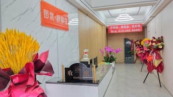 A hotel reception area with a reception desk, a cash register, and a sign indicating a new product introduction.