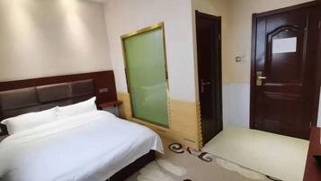 Una habitación de hotel con cama, escritorio, silla y puerta.