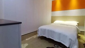 A hotel room with a bed, a desk, and a wall with a vertical orange and white design. - Tuyou Shuxiang Homestay (Lanzhou)