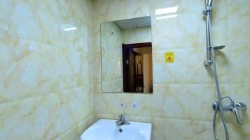 Un baño con lavamanos blanco, espejo y ducha.