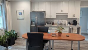A modern kitchen with white cabinets, a built-in oven, and a refrigerator. There is a dining table with chairs and potted plants. - Charming studio in lovely Charlotte with WiFi, AC (Charlotte)