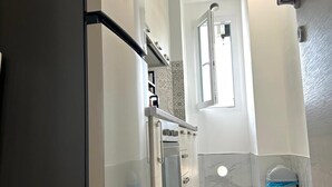 A modern kitchen with stainless steel appliances, a marble backsplash, and a small trash bin. - Luxury B&B Apartment in Parella - Near Turin Center - Métropolitain & Museum (Torino)