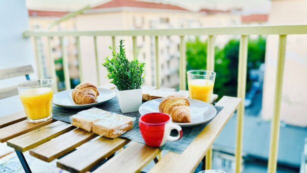 A balcony table with croissants, juice, and a small plant. - Luxury B&B Apartment in Parella - Near Turin Center - Métropolitain & Museum (Torino)