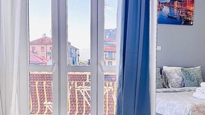 A hotel room with a bed, a bathroom mirror, a window with curtains, and a painting on the wall. - Luxury B&B Apartment in Parella - Near Turin Center - Métropolitain & Museum (Torino)