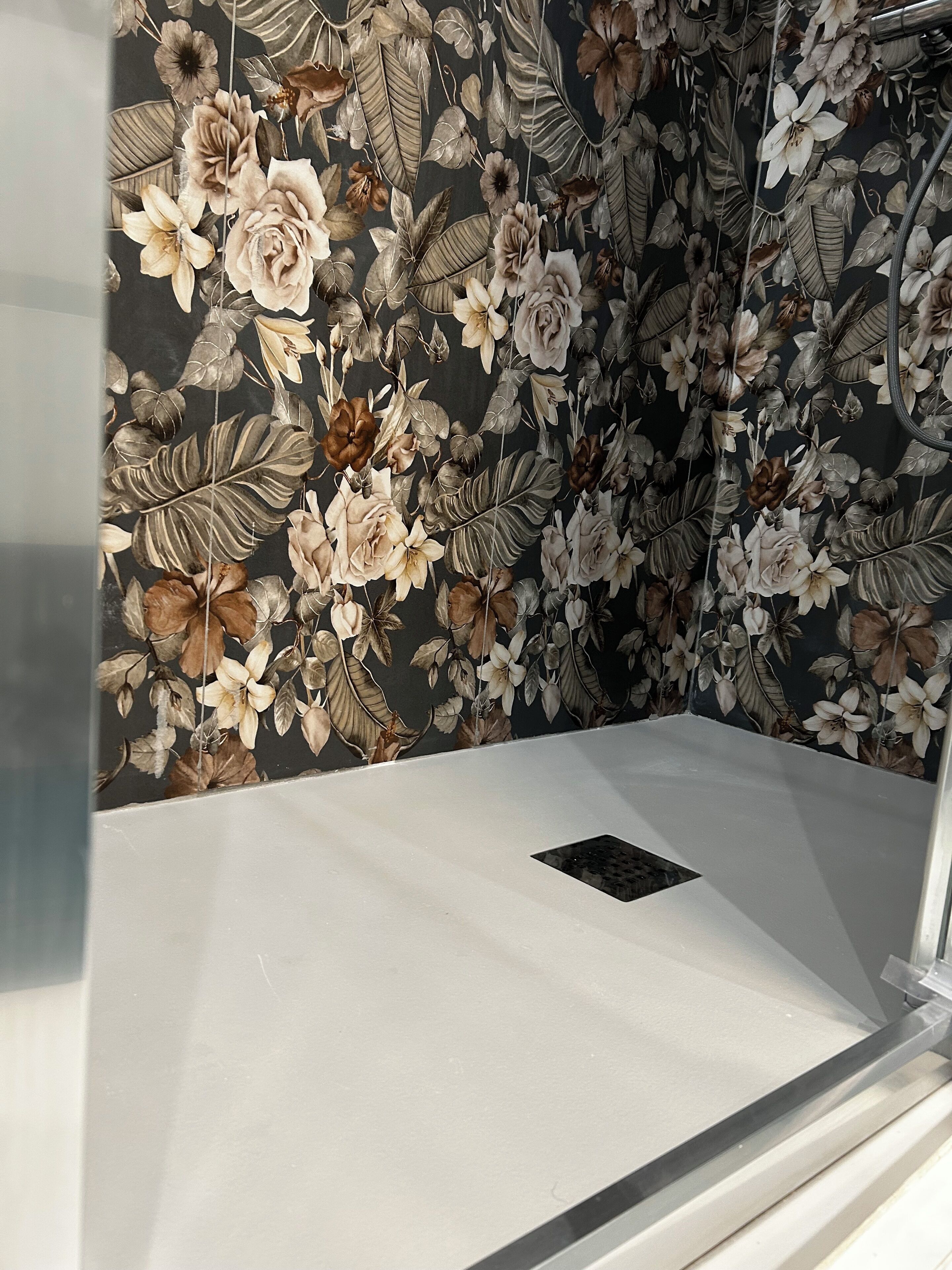 A room with a floral wallpaper, a white bed, and a black drainboard.