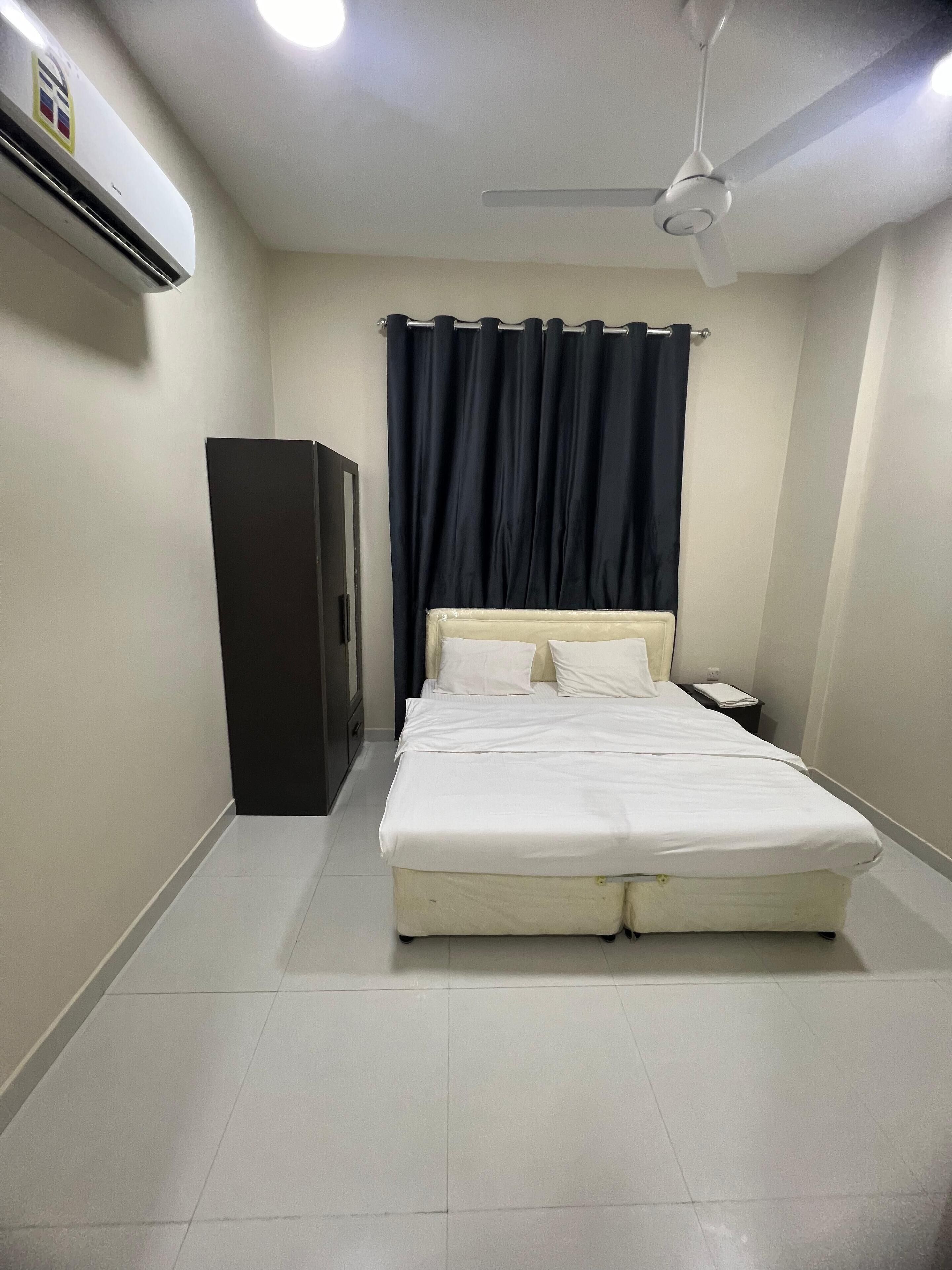 Une chambre à coucher comprenant un lit, une table de chevet, une armoire, un ventilateur de plafond et un appareil de climatisation.